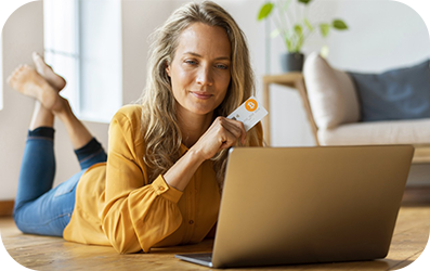 Mujer sosteniendo una tarjeta de crédito mientras mira una computadora portátil