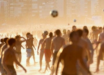 Personas jugando pelota en la playa al atardecer