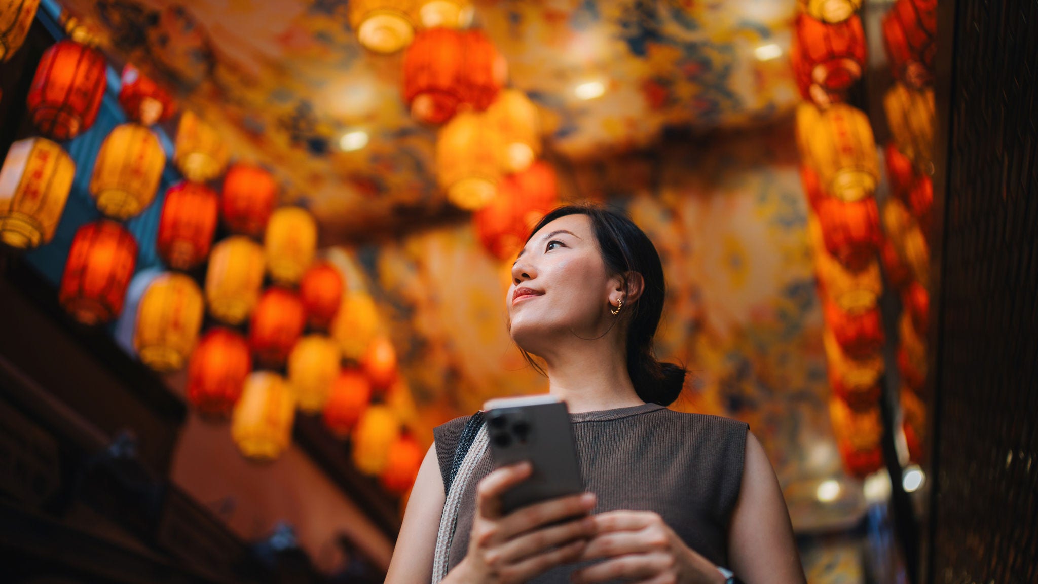 Woman in a brightly lit market holding phone