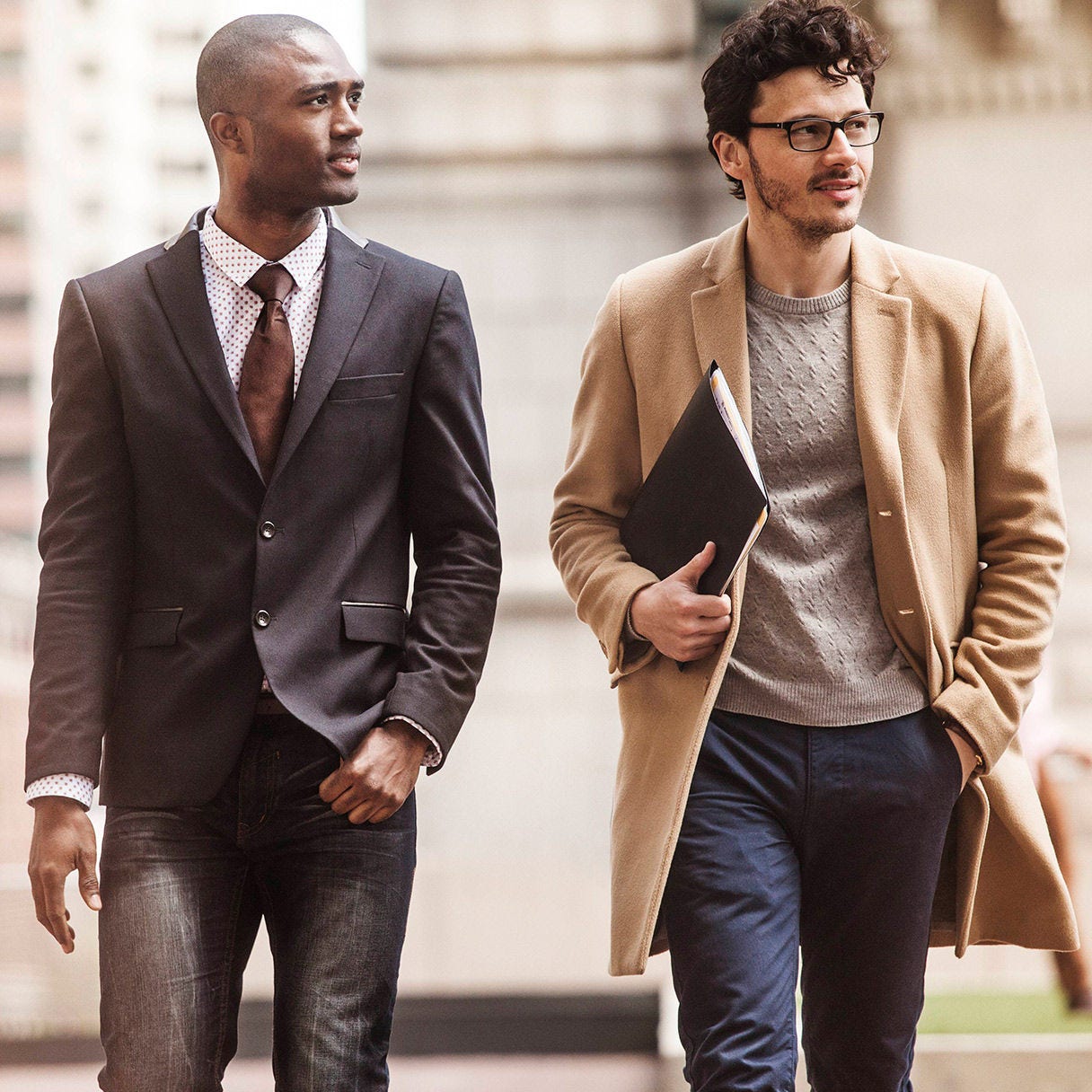 Two professionally dressed coworkers walking and talking outdoors.