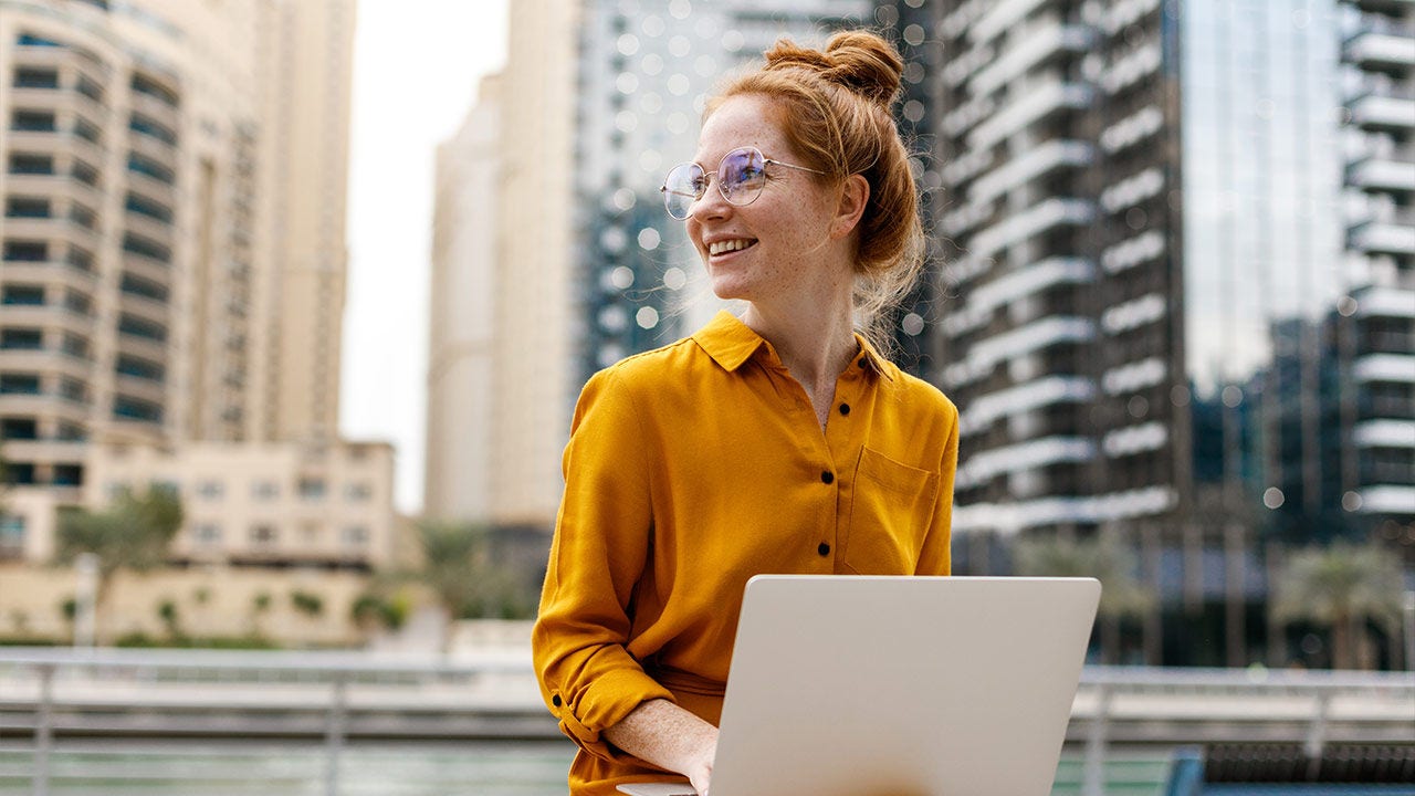 Young woman sitting in marina aria and working on a laptop.