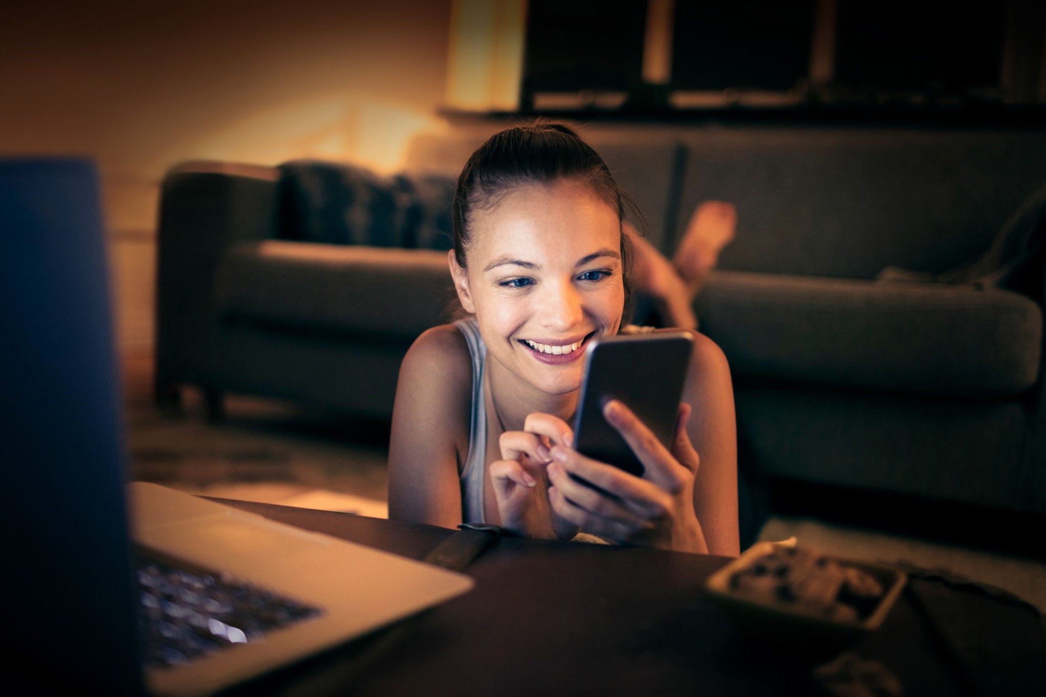 Mujer sonriendo mientras navega en su teléfono móvil