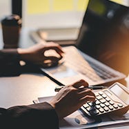 man using a calculator and laptop.