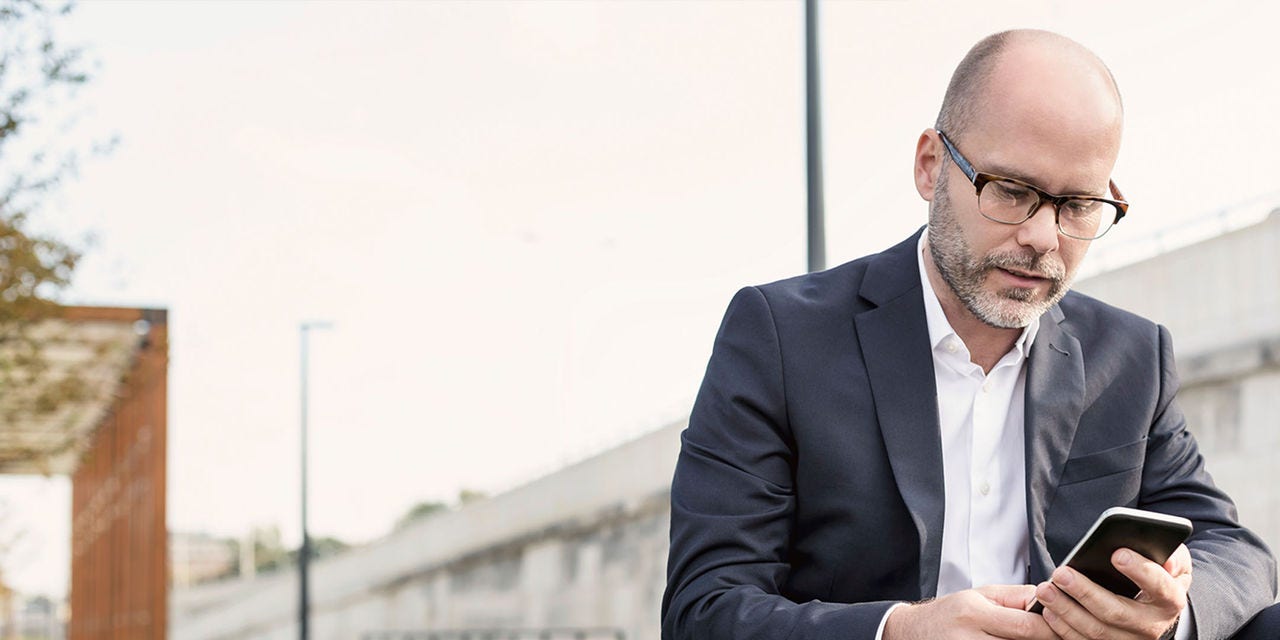 Un homme chauve en costume utilisant son téléphone