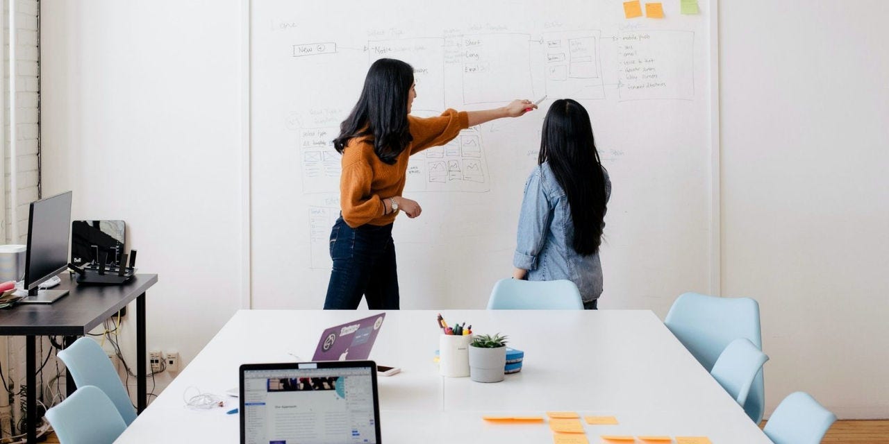 Two women working on white board