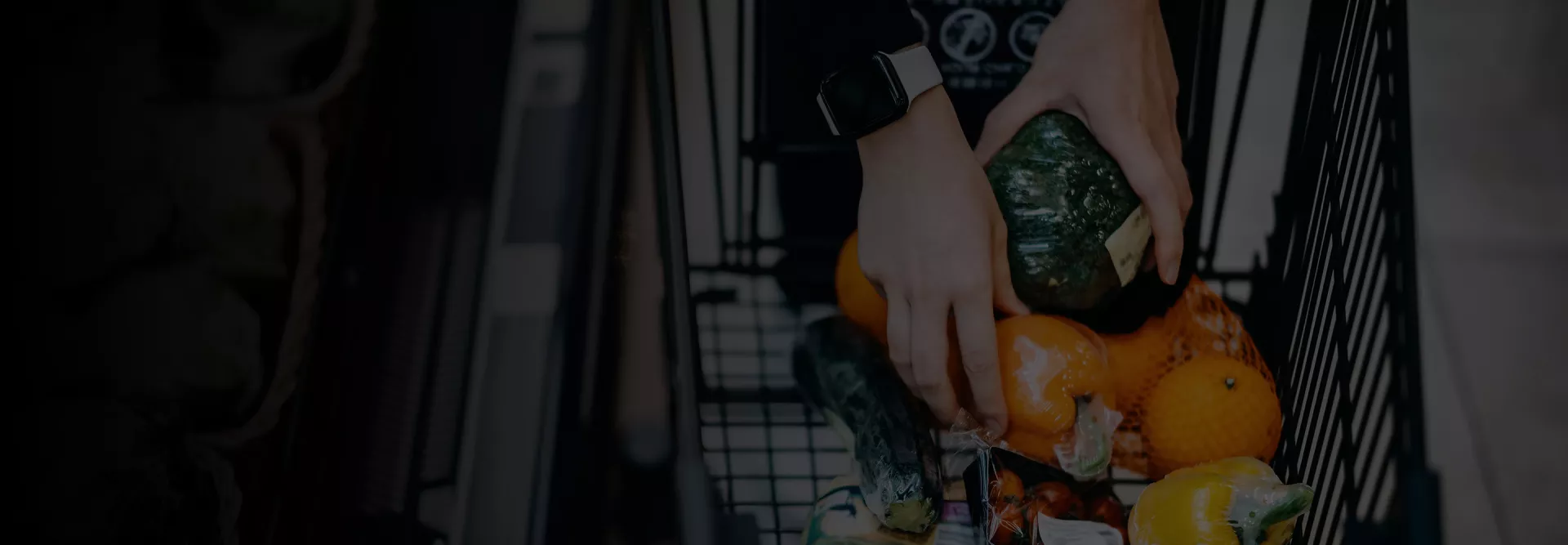 Person's hands inside a shopping cart grabbing packaged vegetables