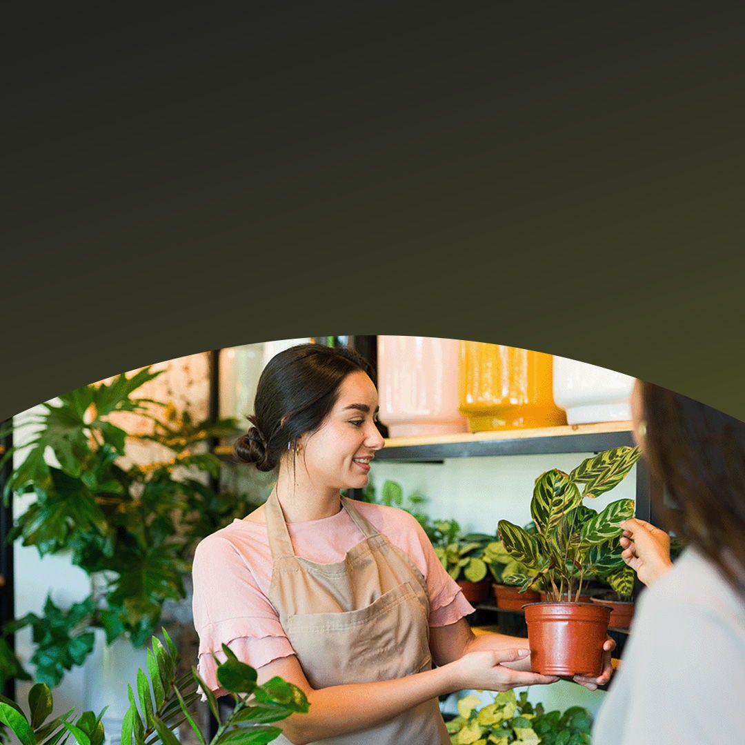 Mujer propietaria de un vivero que vende plantas a un cliente.