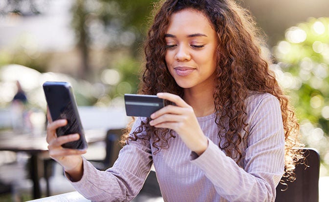 Mujer sosteniendo un teléfono y una tarjeta de crédito.