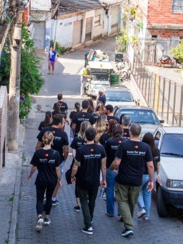 The team of Mastercard volunteers in Force for Good T-shirts walk down a street in the favela. 