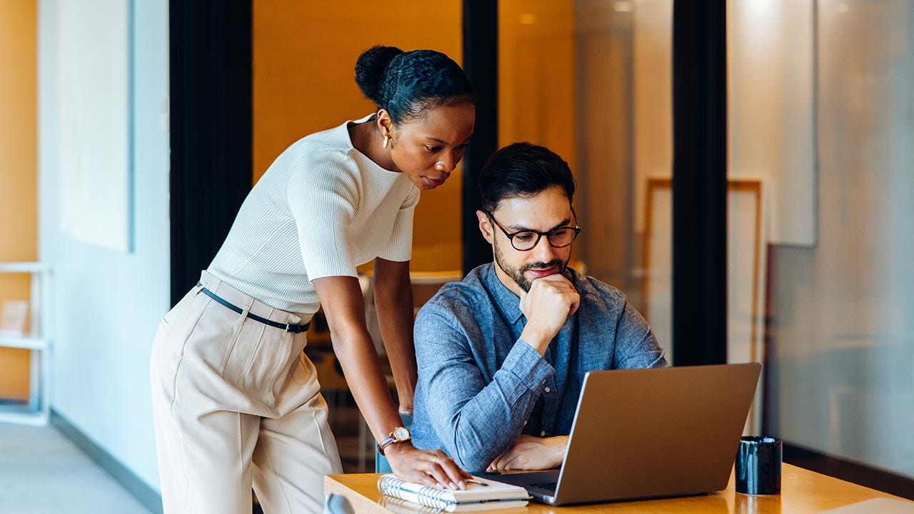 Collègues concentrés sur leur ordinateur portable au bureau.
