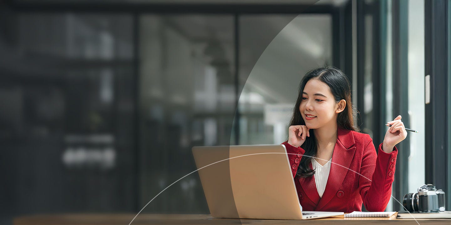 Mujer sosteniendo un bolígrafo mientras mira una laptop en la oficina.