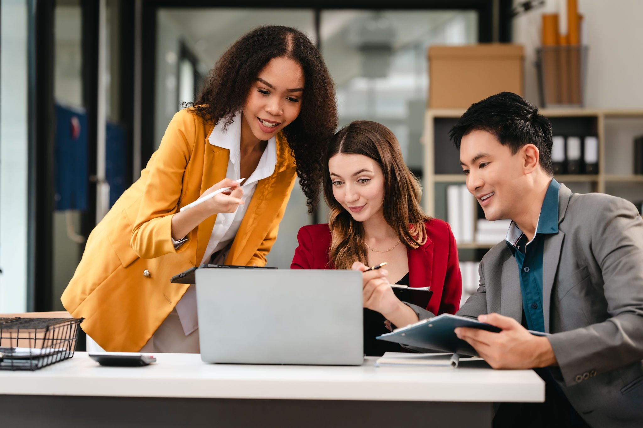 Dos mujeres y un hombre mirando la pantalla de una computadora portátil.