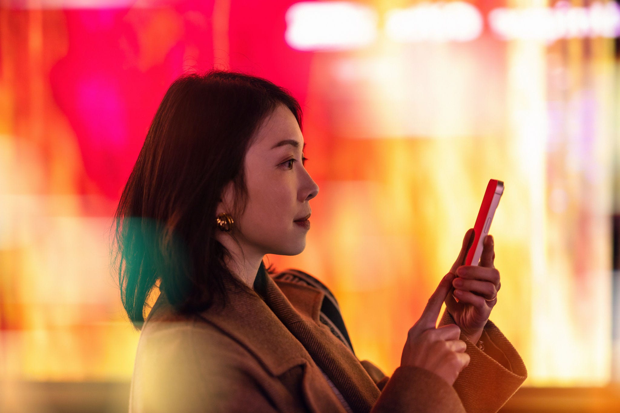 Woman on her phone at night surrounded by lights