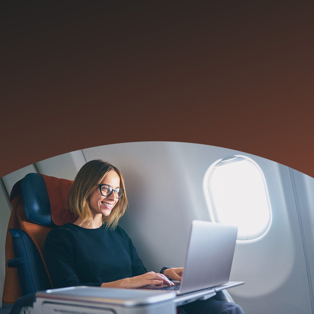 Mujer trabajando en su computadora portátil en un avión. 
