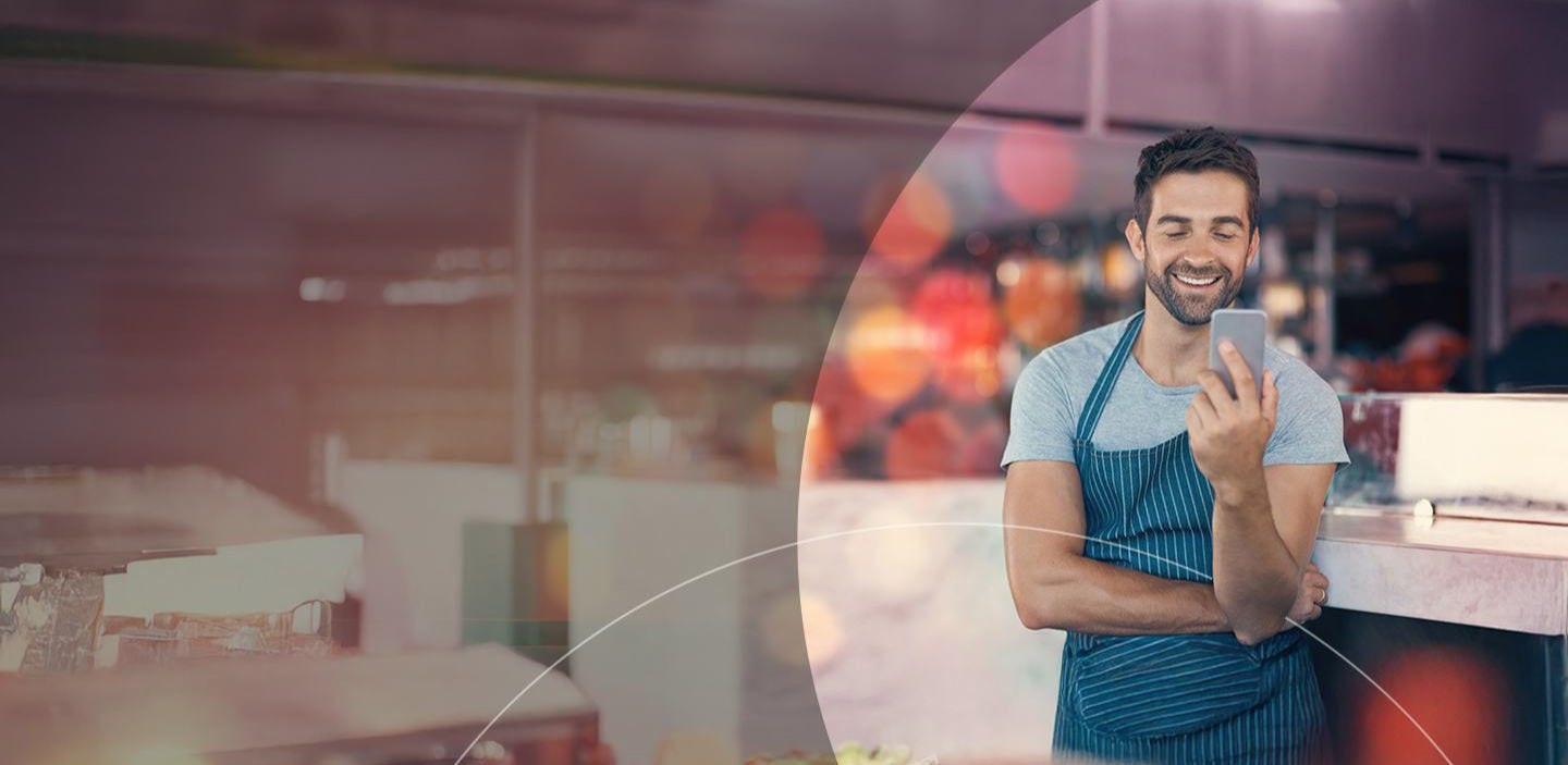 man in apron looking at the mobile phone.