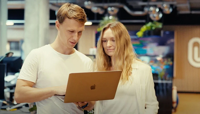 Young man and woman using laptop at work