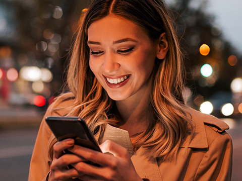 Femme souriant au téléphone à l'extérieur