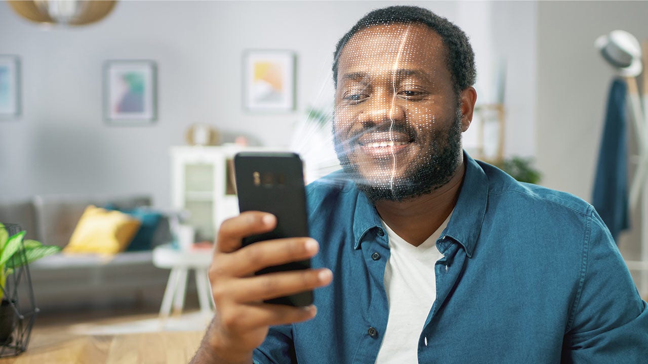 Hombre mirando un teléfono móvil y sonriendo.