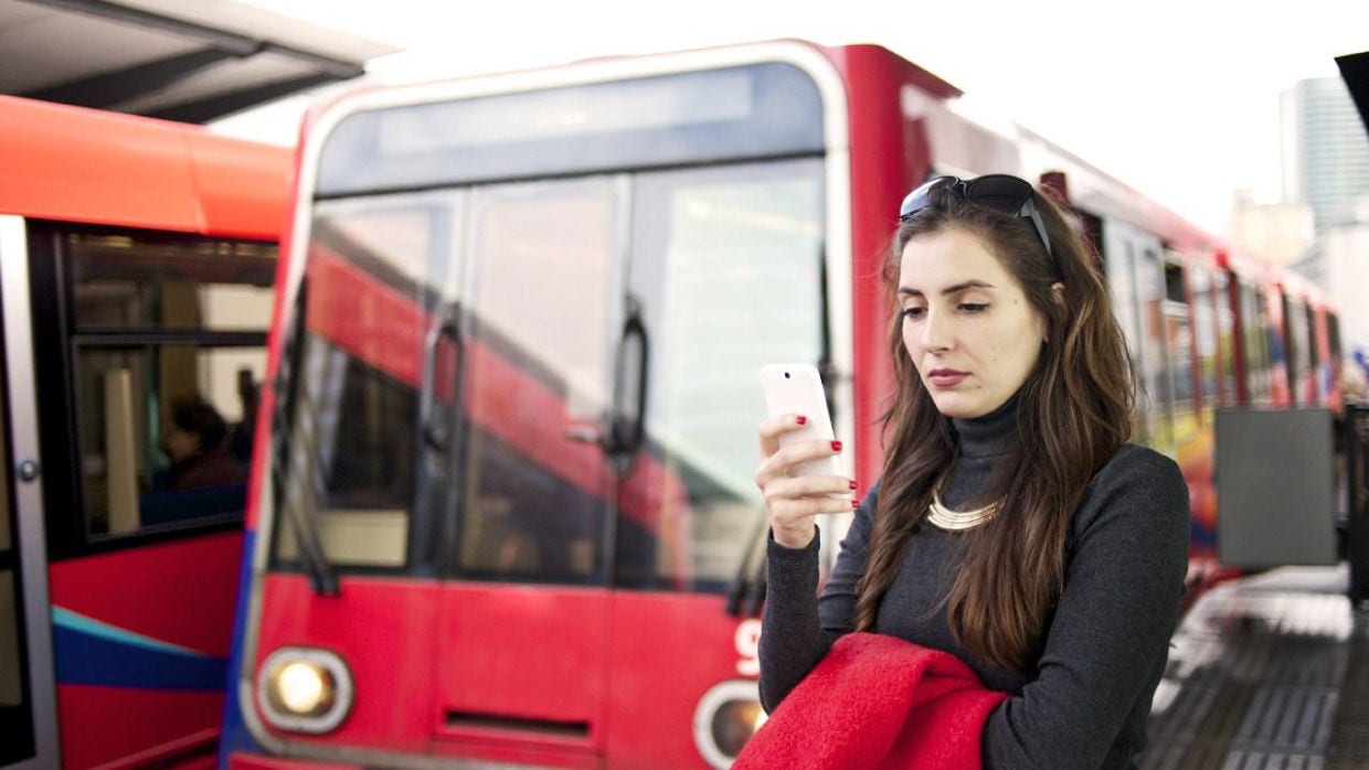 Mujer mirando el teléfono en la parada de autobús.