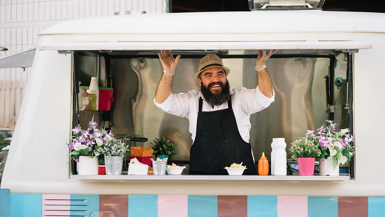 Food truck operator smiling in his truck.