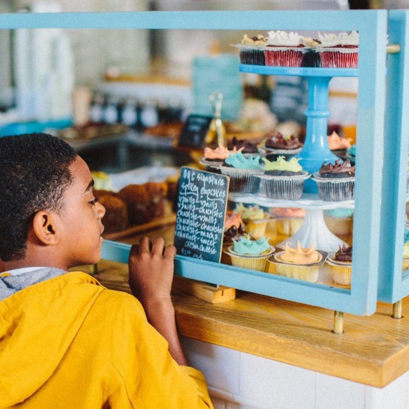 mujer sosteniendo su sombrero frente a una puesta de sol