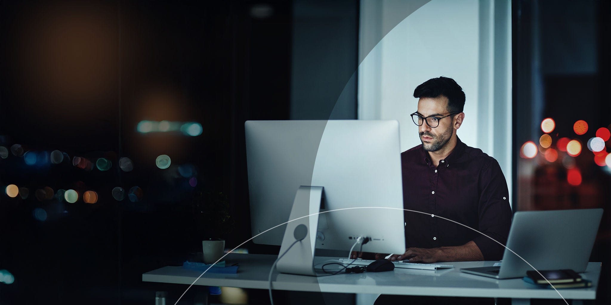Hombre sentado en un escritorio frente a una computadora.
