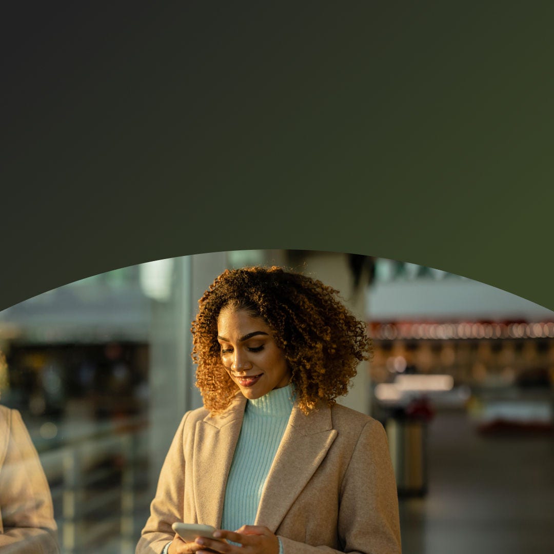 Woman using her phone looking out the window of an office building