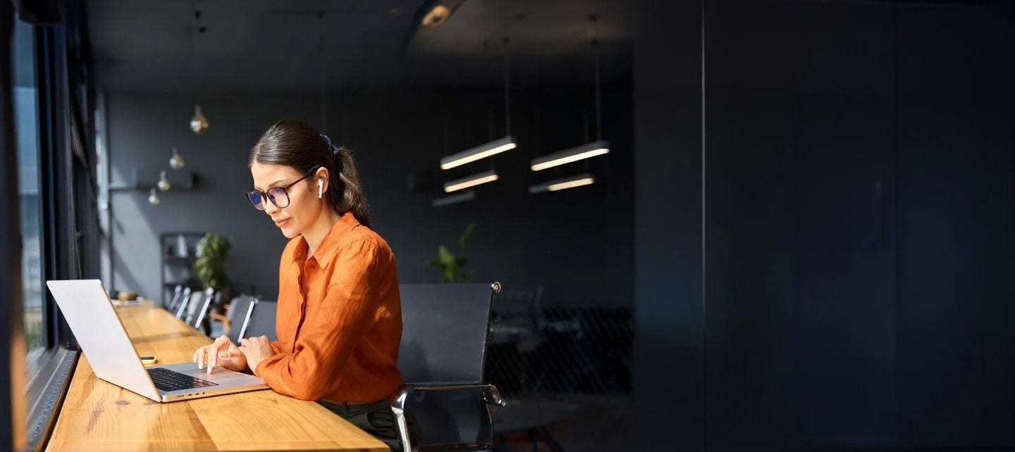 امرأة ترتدي نظارات تعمل على حاسوب محمول