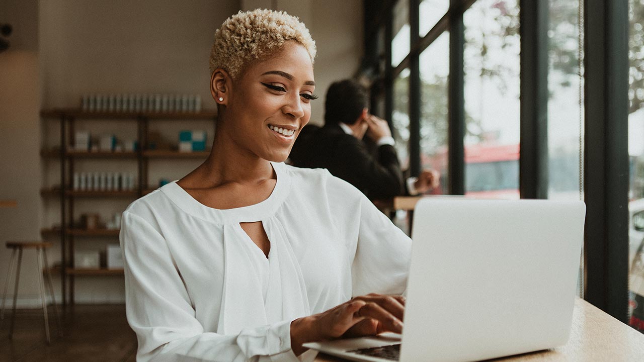 Mujer elegante usando una computadora portátil en un salón.