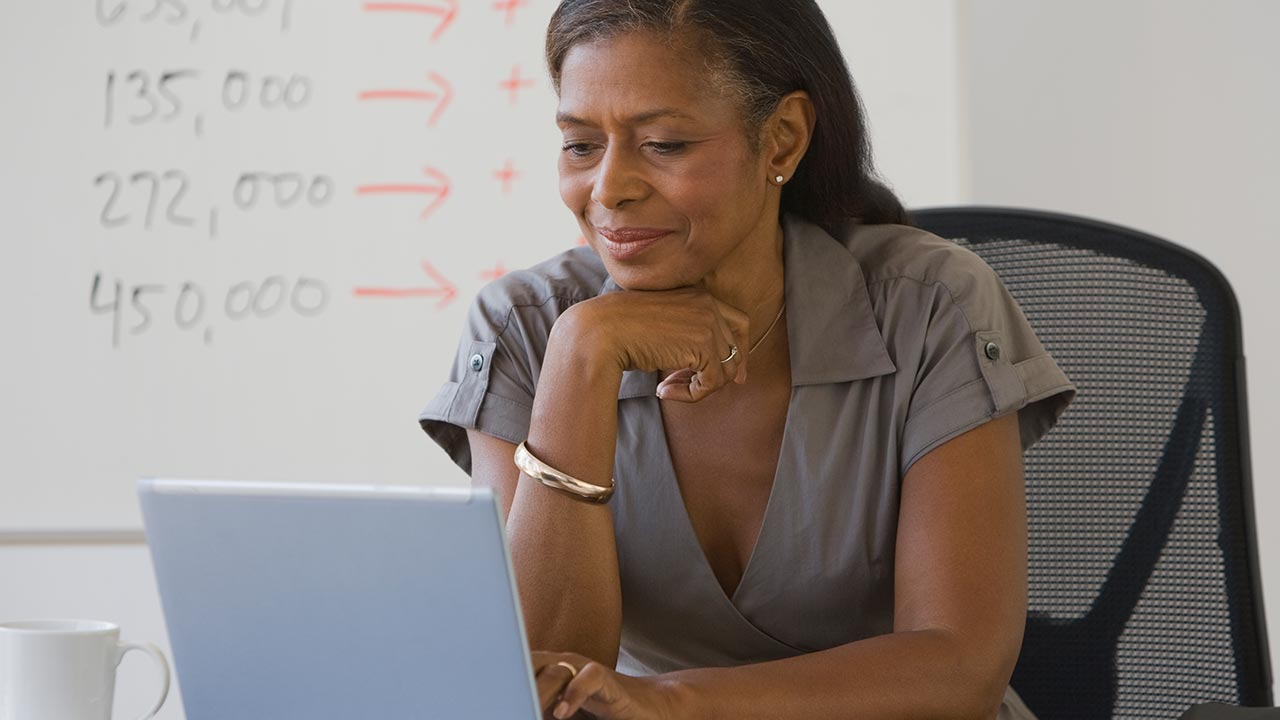 Una mujer de negocios madura mirando una computadora portátil.