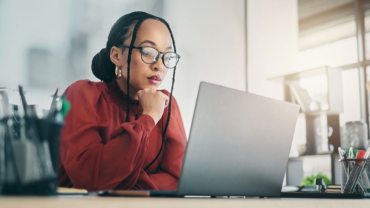 Mujer de negocios enfocada en planificar y leyendo en línea.
