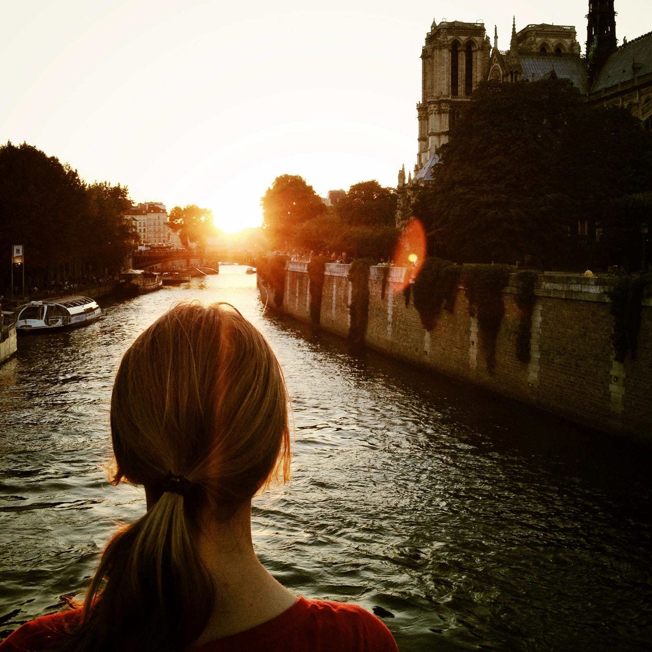 A woman looks over the Seine at sunset. 
