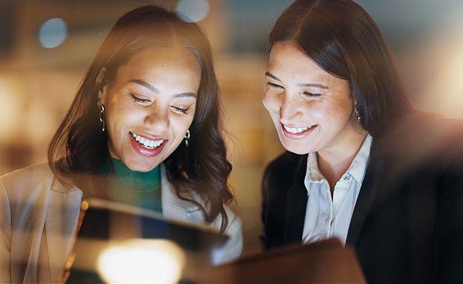 Dos mujeres sonriendo mientras compran en una tableta.