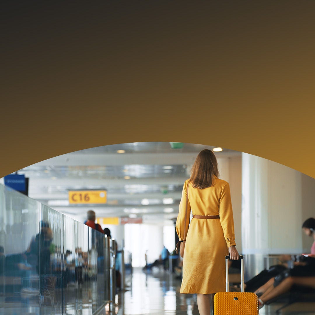 Mujer caminando por un aeropuerto con equipaje. 