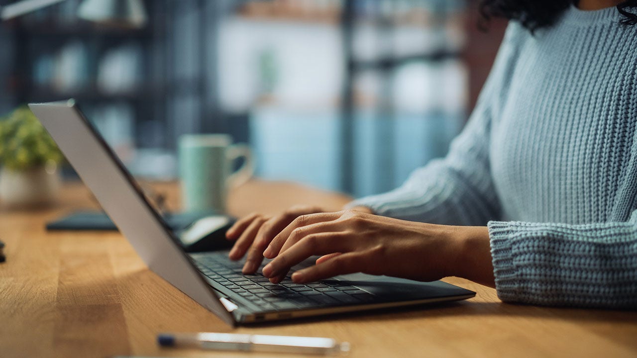 Manos de una mujer especialista trabajando en una computadora portátil.