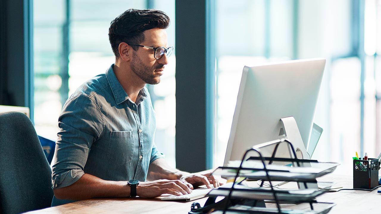 Jeune homme d’affaires concentré utilisant un ordinateur dans un bureau moderne.