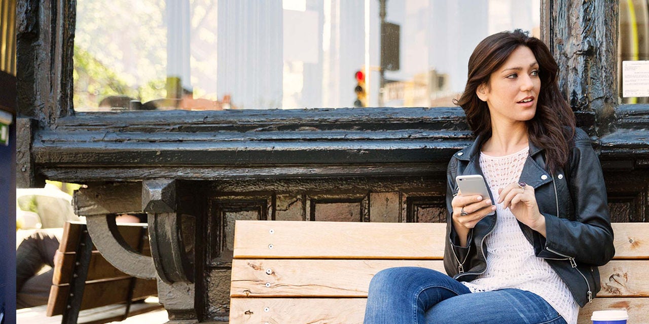 Femme assise sur un banc avec un téléphone