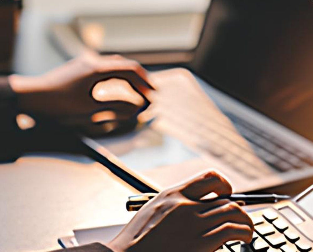 Une personne travaillant à son bureau avec une calculatrice et un ordinateur portable.