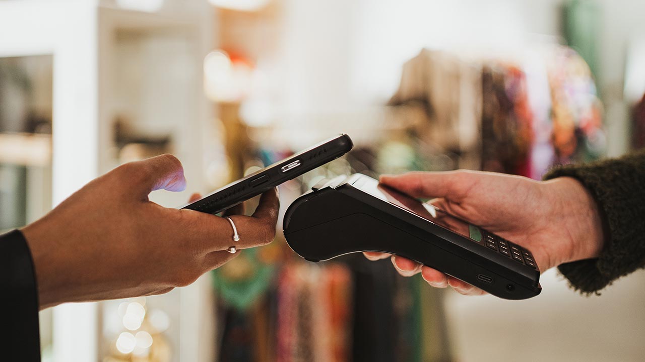 Phone tapping a payment terminal in retail store.