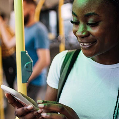 Una persona sonriendo a un teléfono inteligente dentro de un colectivo