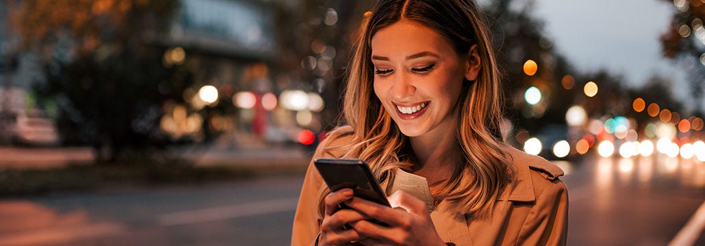Femme souriant au téléphone en ville