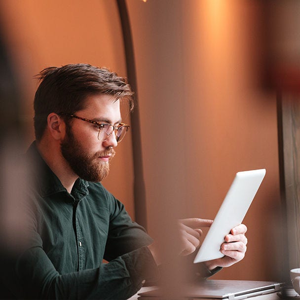 A man working on a tablet at a desk.