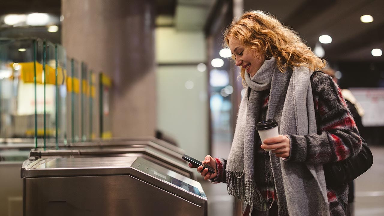 Young woman tapping subway turnstile.