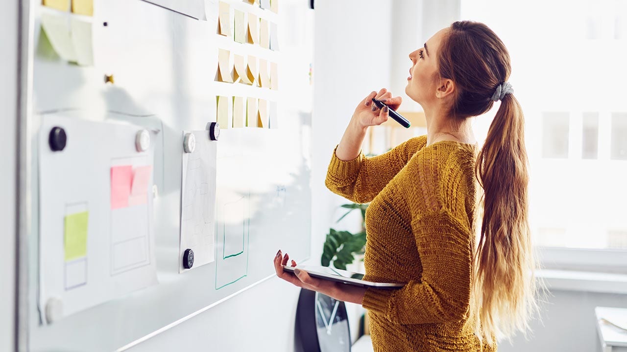 Femme réfléchissant devant un tableau blanc.