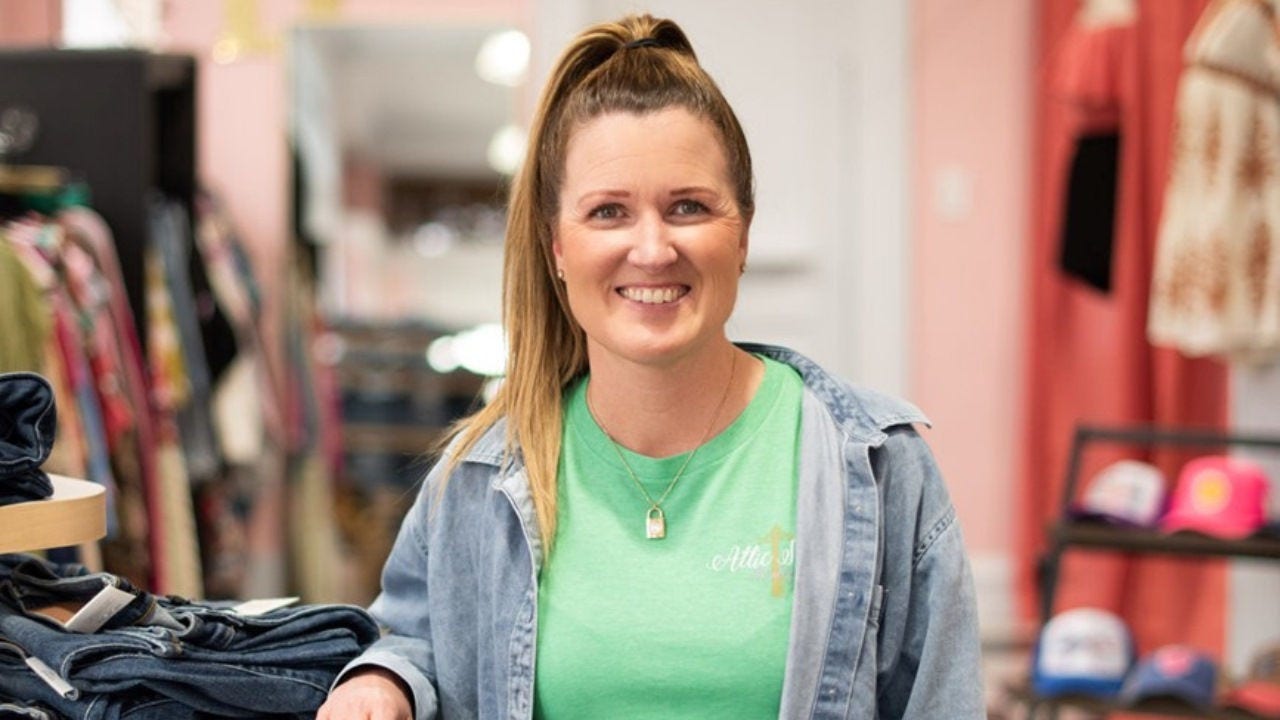 Kristin Morron smiles next to a clothing display in Attic Salt. 