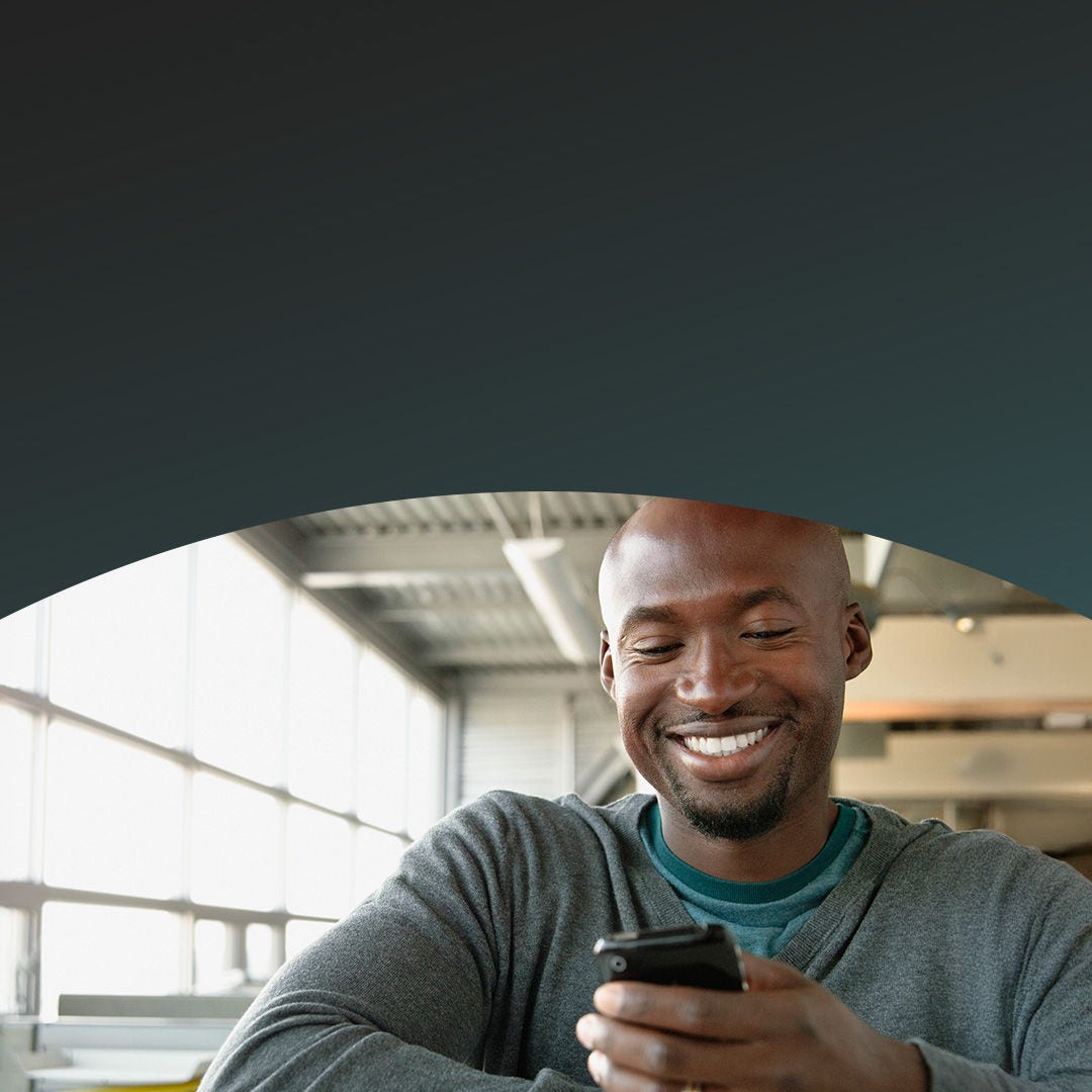 Un homme dans un bureau regarde son téléphone portable.