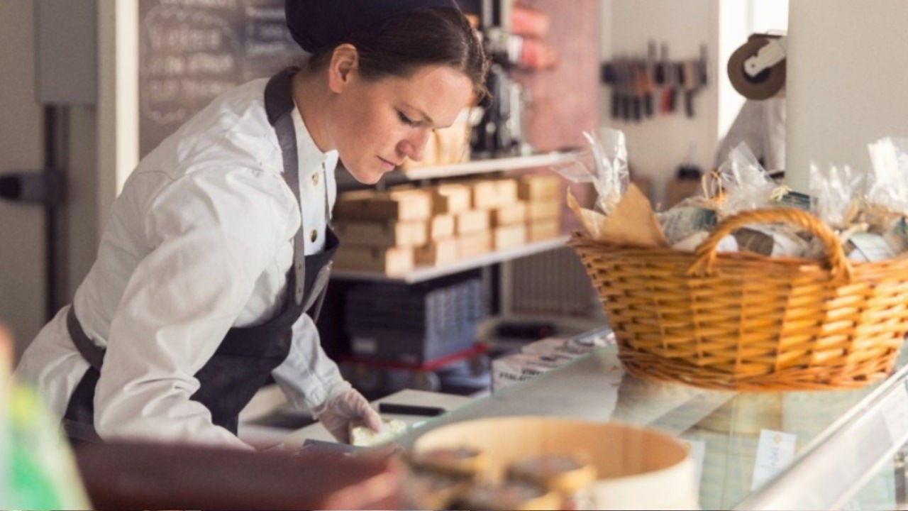 Une femme en tablier fait de la paperasserie sur le comptoir d'un magasin. 