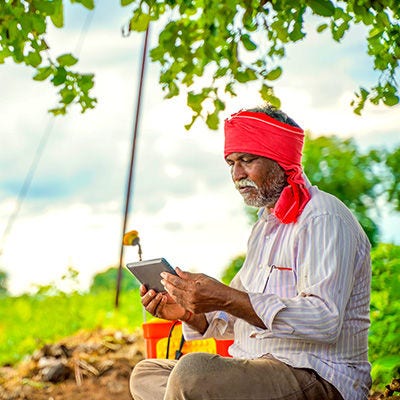 Man looking at tablet while sitting at a farm.