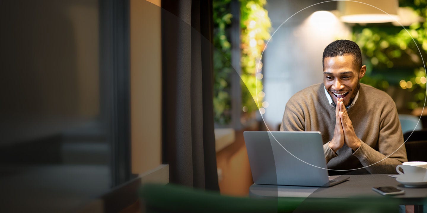 Joven empresario usando la computadora portátil sentado en un café.